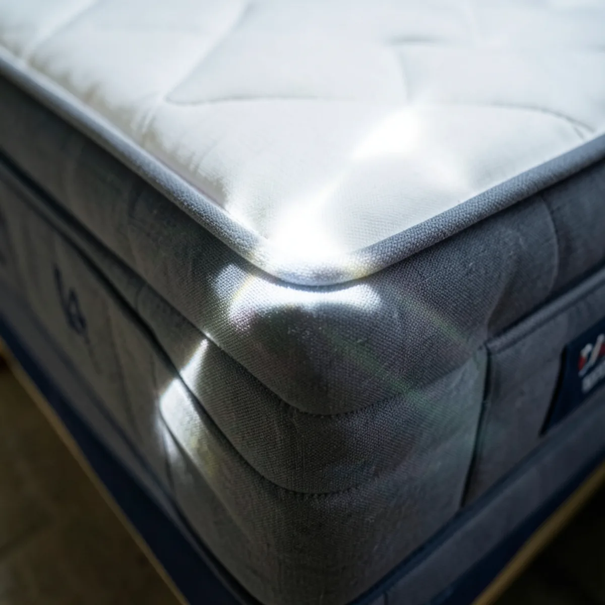 High-intensity LED flashlight illuminating the underside edge of a mattress seam